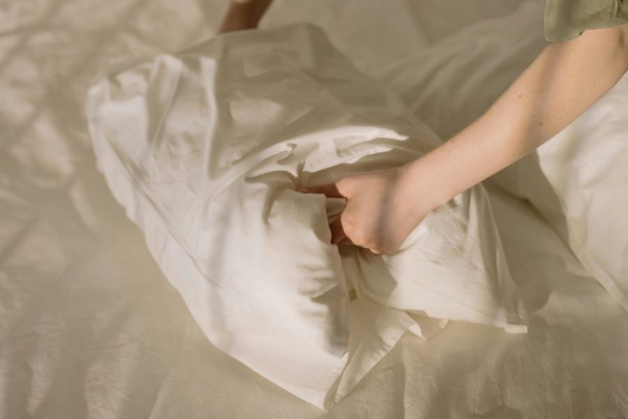 Close-up of clean white linens in a cozy bedroom setting, emphasizing comfort and cleanliness.